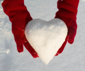 Red mittens holing a heart shaped snowball