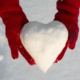 Red mittens holing a heart shaped snowball